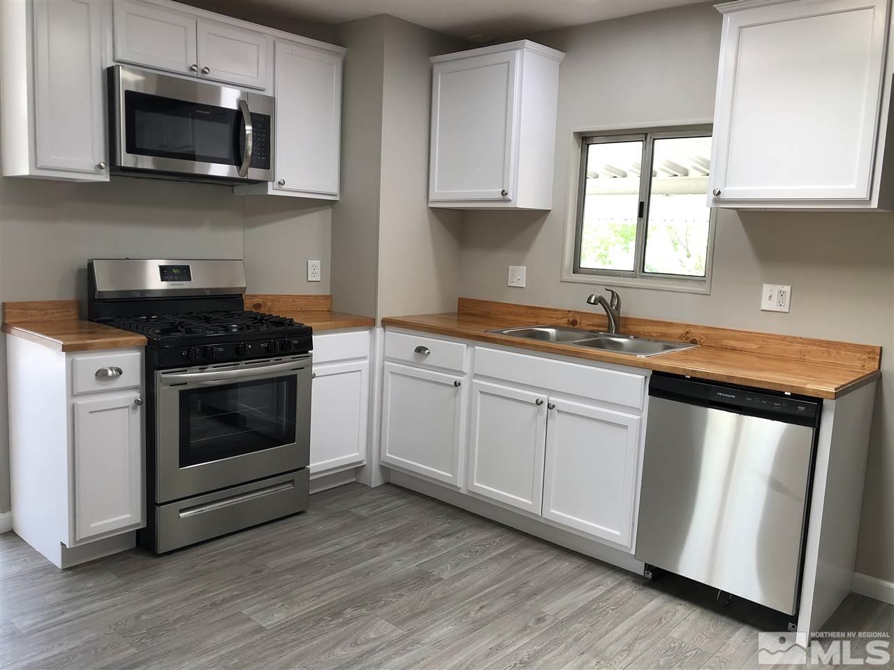 14060 Rhyolite Circle, Unit 89521 Reno, NV 89521 - Photo 6 of 18 a kitchen with stainless steel appliances granite countertop a sink a stove a microwave and wooden cabinets