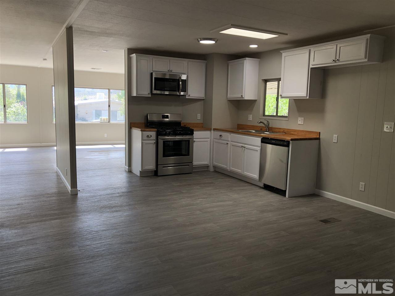 14060 Rhyolite Circle, Unit 89521 Reno, NV 89521 - Photo 7 of 18 a kitchen with granite countertop a stove top oven a sink dishwasher a refrigerator and a dining table with wooden floor