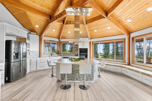 a dining room with stainless steel appliances a wooden floor and a large window