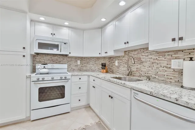 a kitchen with granite countertop white cabinets white stainless steel appliances with a sink and dishwasher