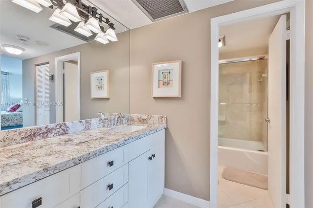 a bathroom with a granite countertop sink a mirror and a shower