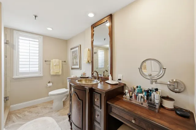 a bathroom with a granite countertop sink mirror vanity and toilet