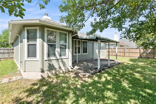 a view of a white house with large windows and a small yard