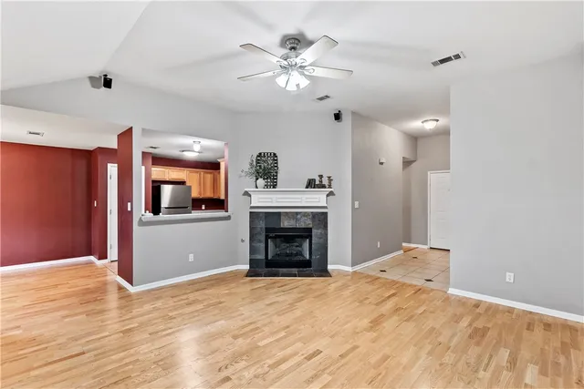 a view of an empty room with chandelier fan and fire place
