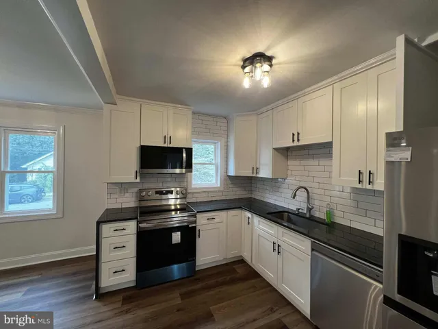 a kitchen with cabinets stainless steel appliances a sink and wooden floor