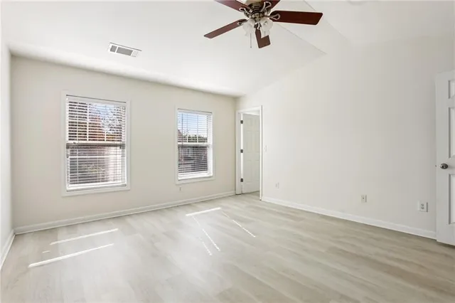 an empty room with closet and a ceiling fan