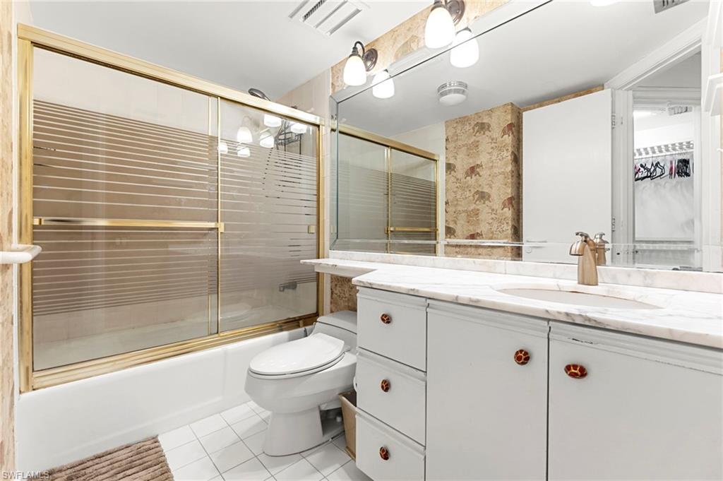 305 La Peninsula Boulevard, Unit 305 Naples, FL 34113 - Photo 18 of 23 a bathroom with a granite countertop sink toilet a mirror and shower