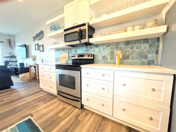 a large kitchen with stainless steel appliances kitchen island granite countertop a sink dishwasher and a stove with wooden floor