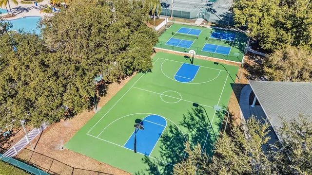 a view of a tennis ground with large trees