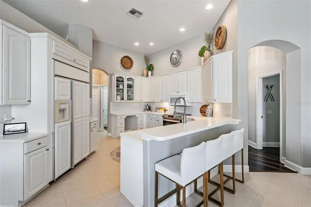 a large white kitchen with a sink and refrigerator