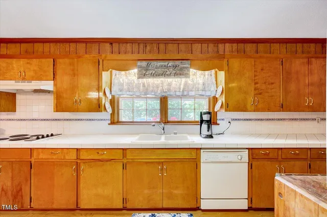 a kitchen with stainless steel appliances a stove a sink dishwasher and cabinets with wooden floor