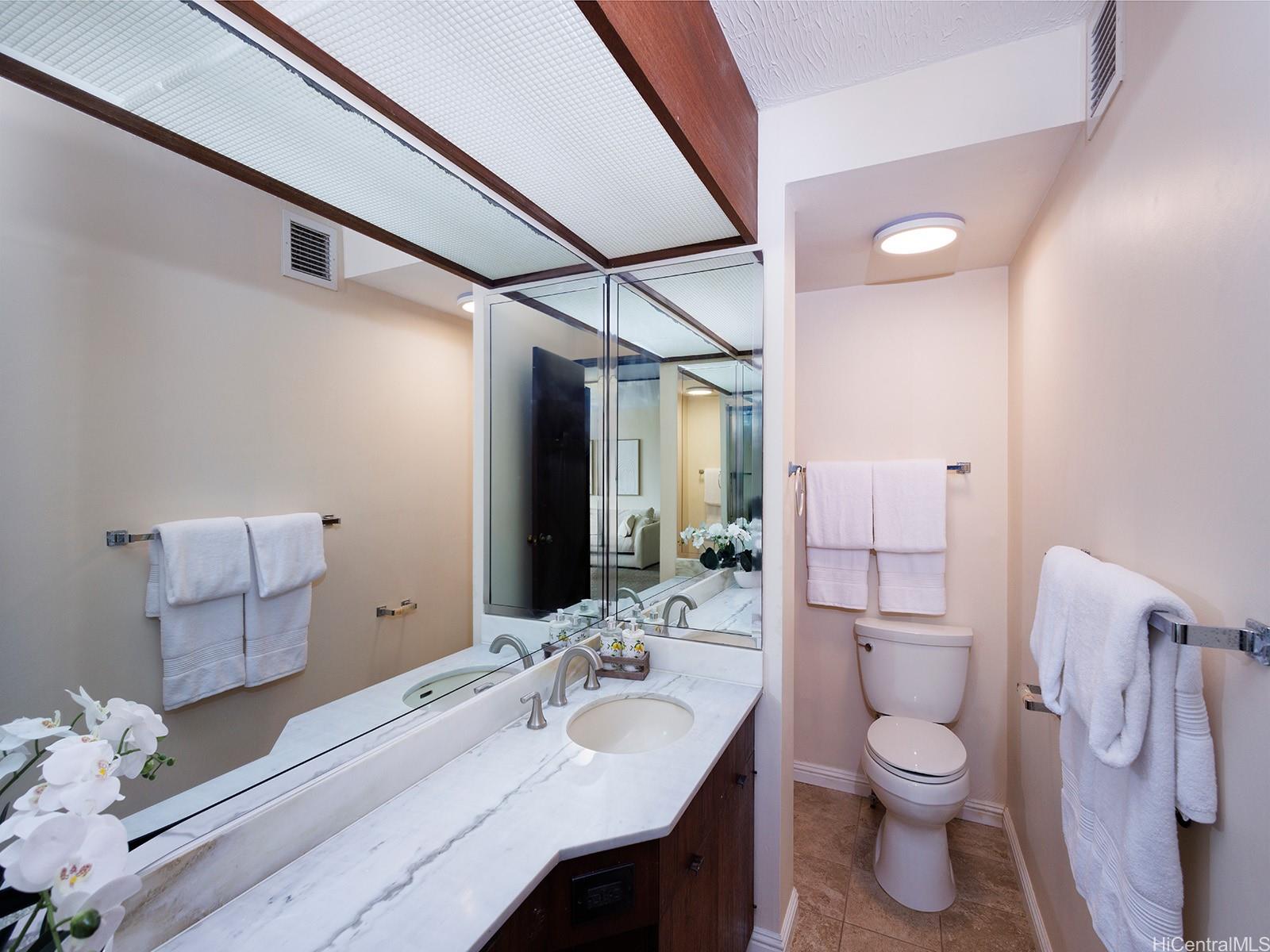 500 Lunalilo Home Road, Unit 13B Honolulu, HI 96825 - Photo 12 of 17 a bathroom with a granite countertop toilet sink and a mirror