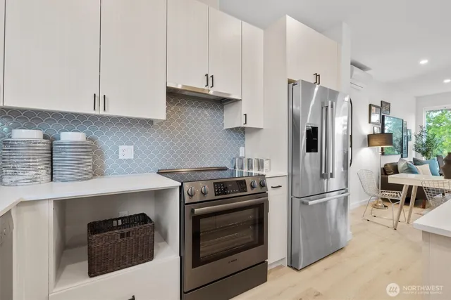 a kitchen with stainless steel appliances kitchen island granite countertop a stove a sink a refrigerator and white cabinets with wooden floor