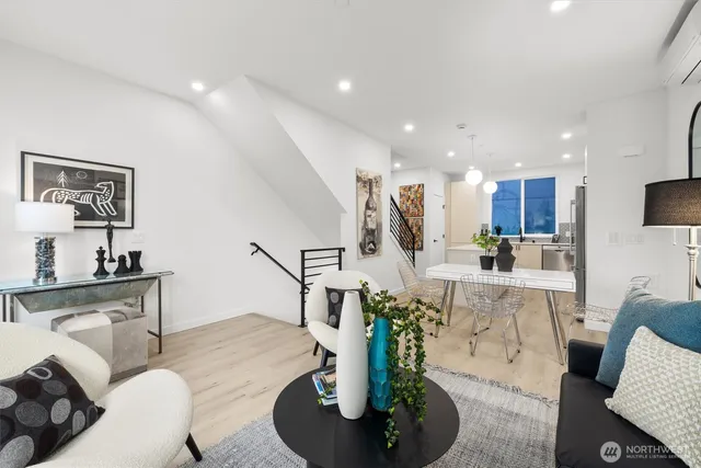 a living room with furniture kitchen view and a wooden floor