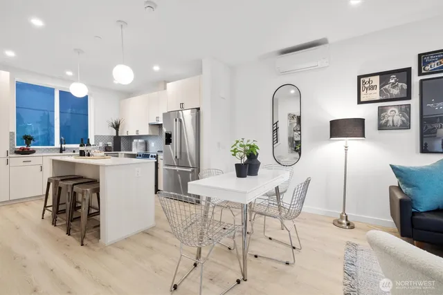 a kitchen with stainless steel appliances kitchen island granite countertop a dining table chairs and white cabinets