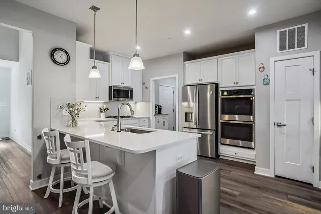 a kitchen with granite countertop a sink cabinets stainless steel appliances and a refrigerator