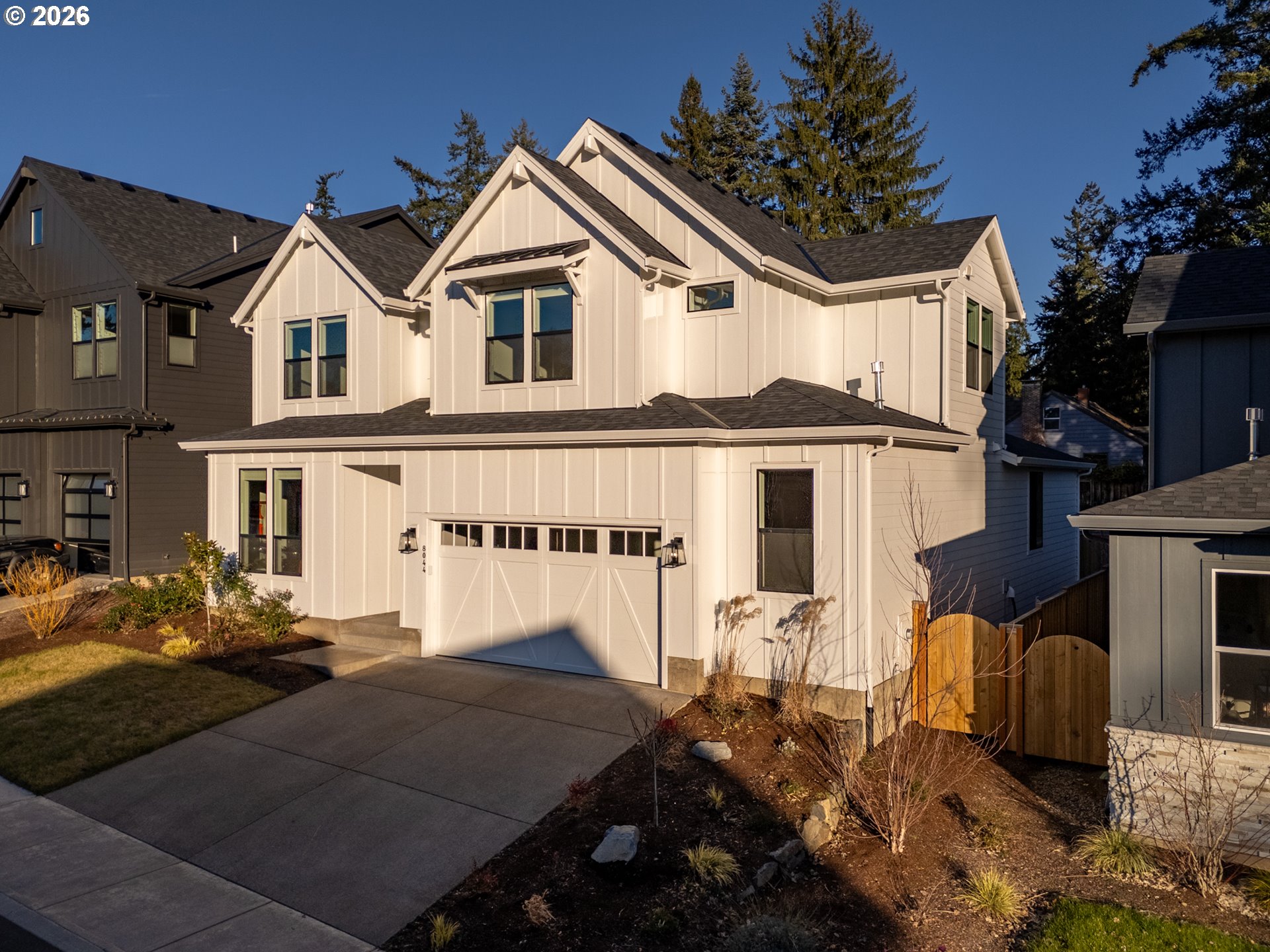 8044 Southwest Knudsen Place Portland, OR 97223 - Photo 4 of 46 a view of a white house with large windows and a yard with plants