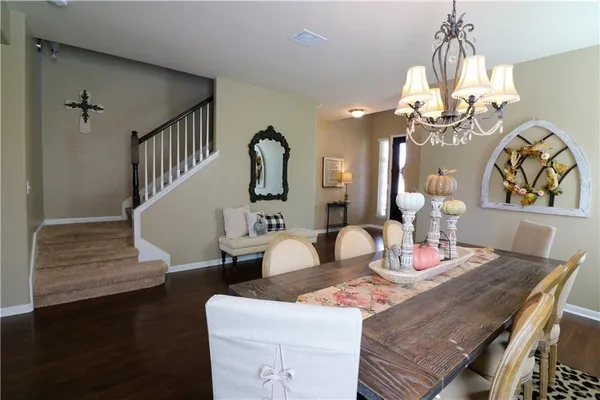 a dining room with wooden floor a chandelier a wooden table and chairs