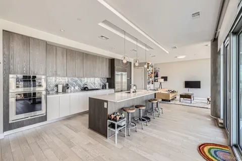 a kitchen with stainless steel appliances granite countertop a stove top oven a sink a dining table and chairs with wooden floor
