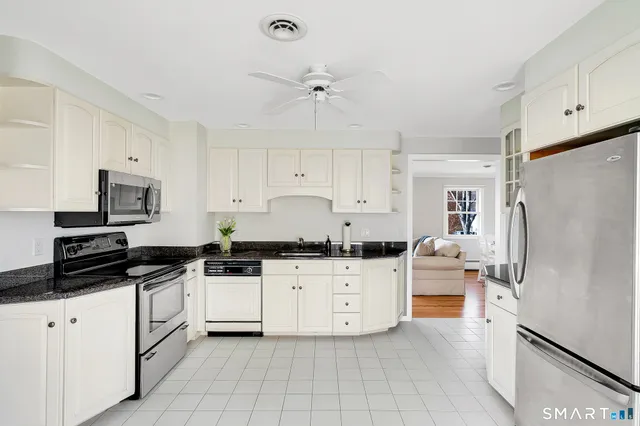 a kitchen with granite countertop a refrigerator sink and white cabinets
