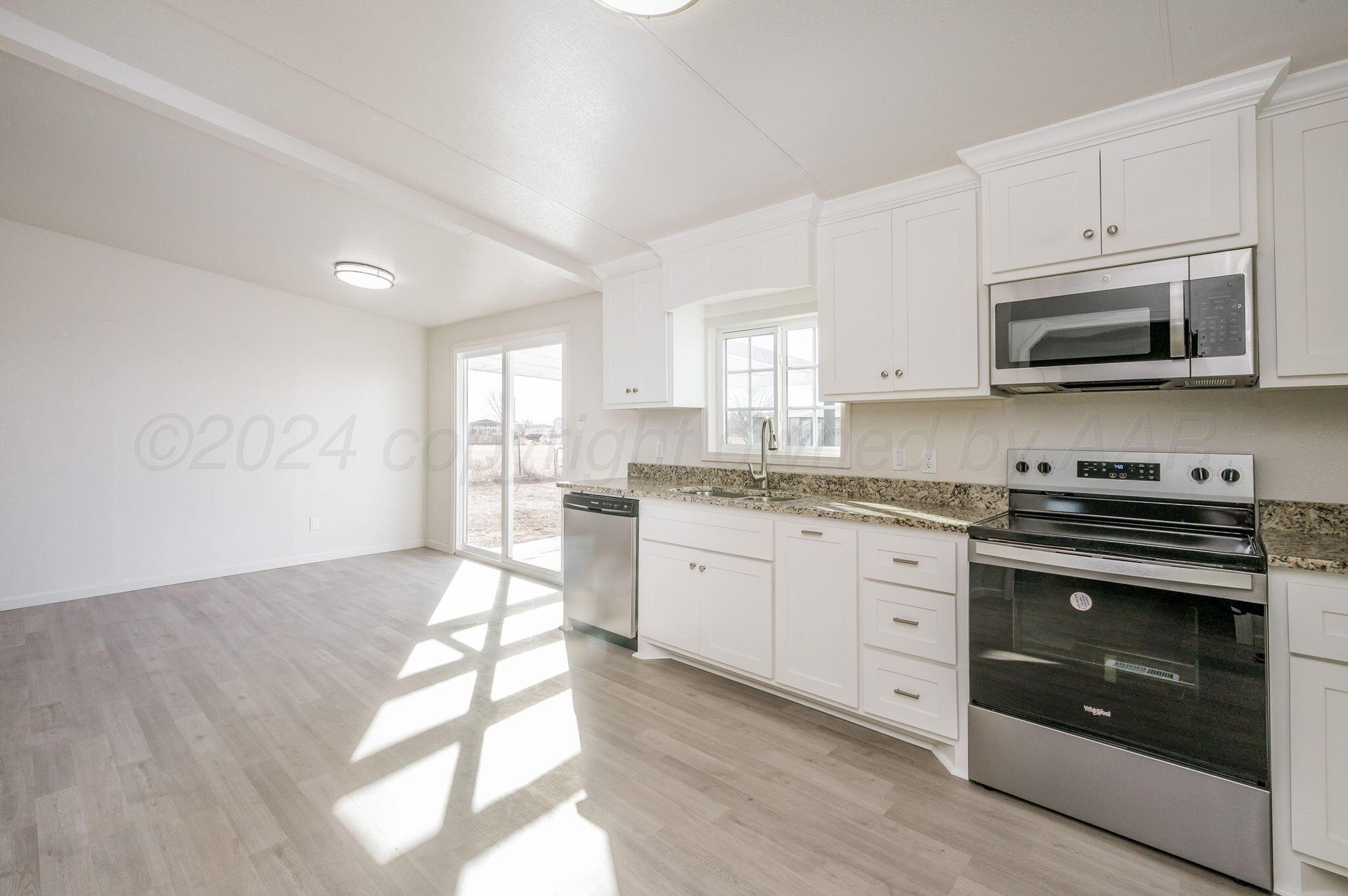 401 West Plantation Road Amarillo, TX 79118 - Photo 6 of 23 a kitchen with granite countertop a stove a sink and a microwave