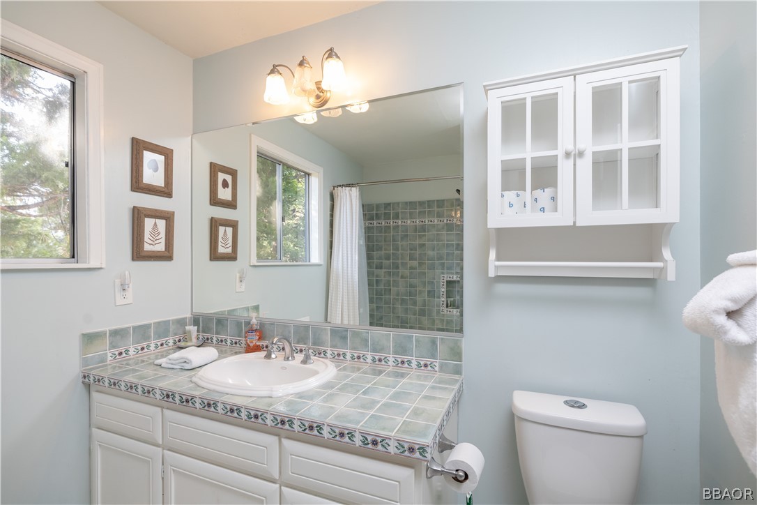 841 Golf Course Road Lake Arrowhead, CA 92352 - Photo 27 of 43 a bathroom with a granite countertop toilet sink and mirror