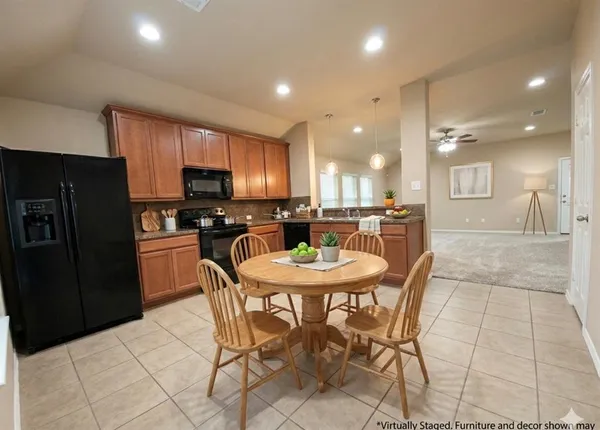 a kitchen with stainless steel appliances kitchen island granite countertop a refrigerator a stove a sink a dining table and chairs