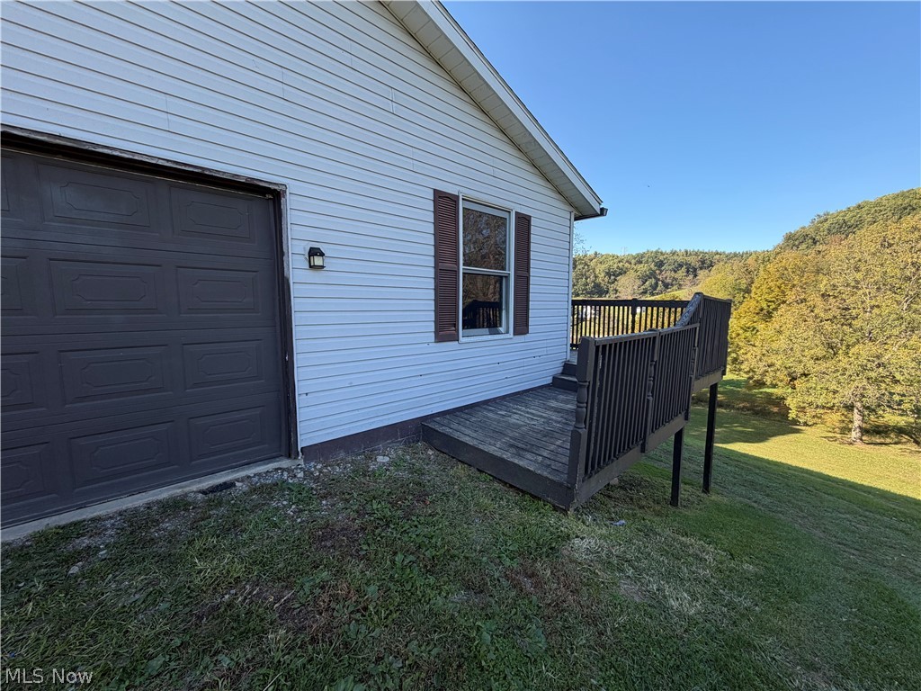 3950 Wolf Road Southwest Port Washington, OH 43837 - Photo 37 of 45 Exterior with horizontal siding, an attached garage with a dark panel door, a side window with dark shutters, and a wood deck with dark railing