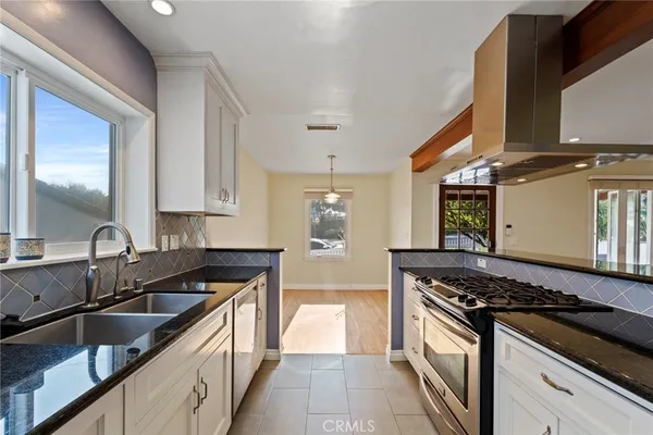 a kitchen with granite countertop a sink stove and cabinets