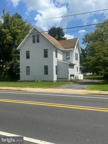 a view of a white house with a yard and large trees