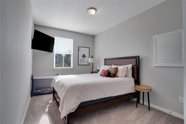 a bedroom with a bed a flat screen tv and window