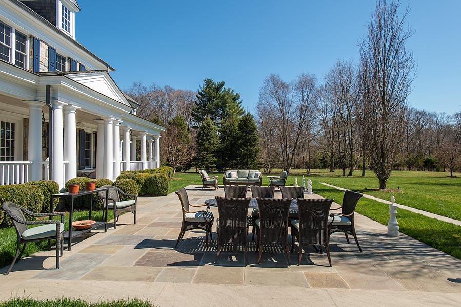 1480 Ponus Ridge Road New Canaan, CT 06840 - Photo 21 of 22 a view of a patio with a dining table and chairs with a garden