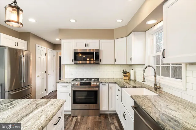 a kitchen with kitchen island a refrigerator a stove a counter space and wooden floor