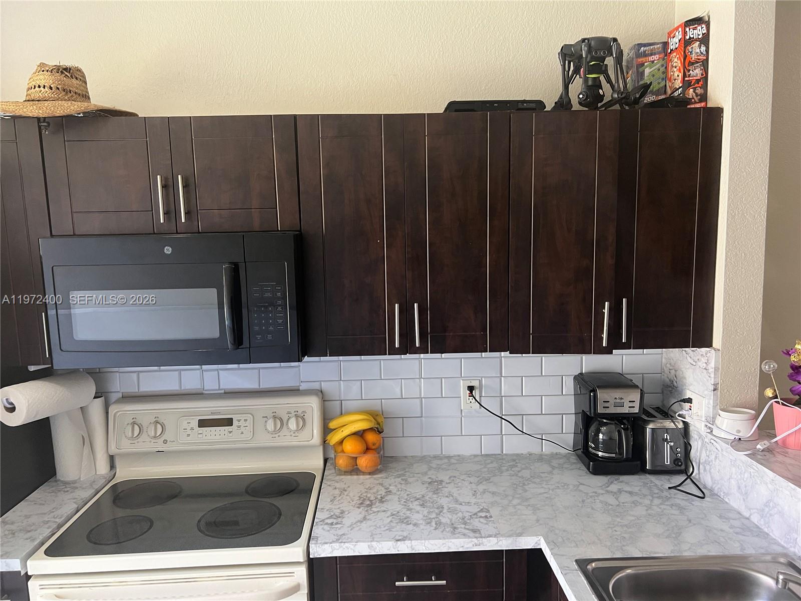 95 Southwest 15th Road Homestead, FL 33030 - Photo 12 of 42 a kitchen with wooden cabinets a sink and a stove