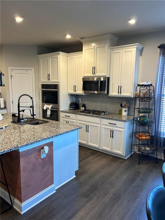 5860 Stargazer Way Cumming, GA 30028 - Photo 12 of 36 a kitchen with stainless steel appliances kitchen island granite countertop a stove a sink and a microwave