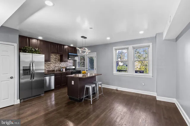 a kitchen with stainless steel appliances granite countertop a refrigerator a sink dishwasher a stove and a refrigerator with wooden floor