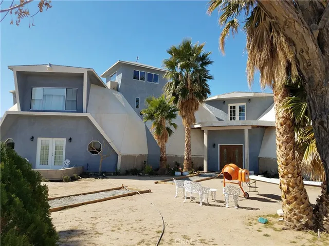 a view of a white house with a yard and palm trees
