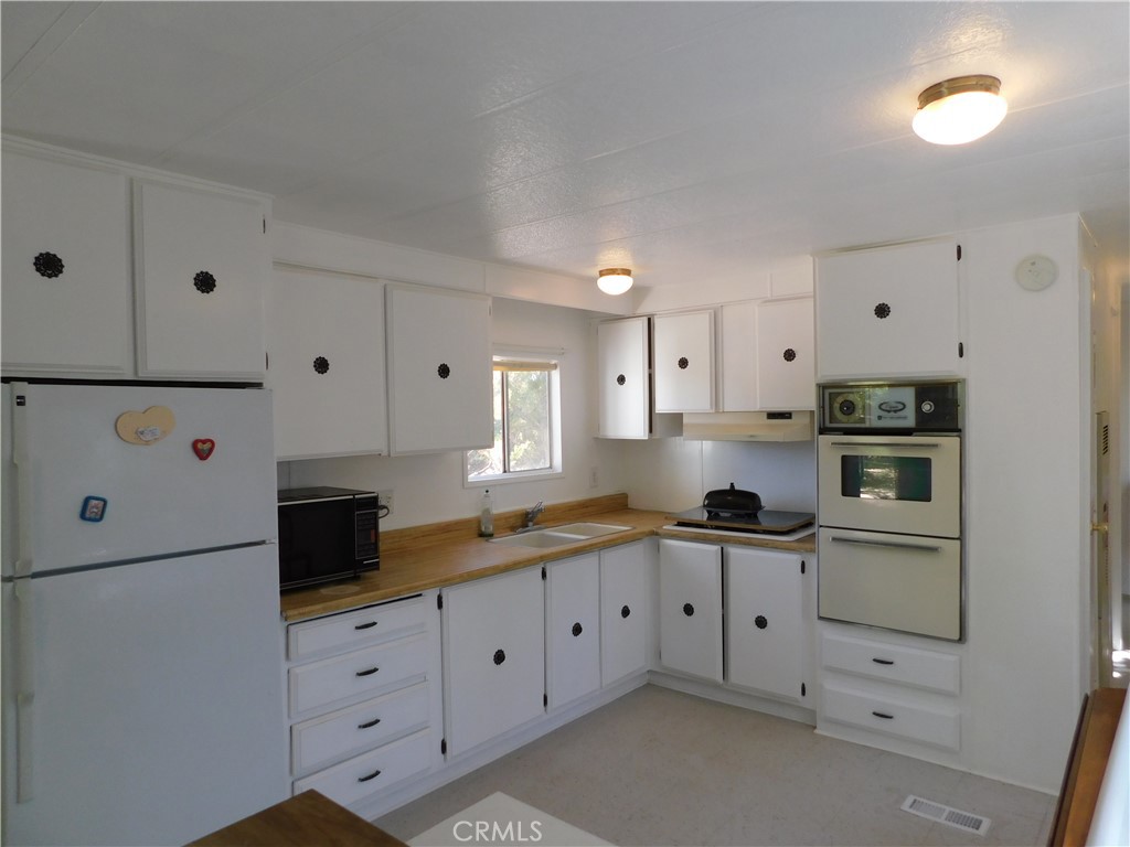 45985 Cottonwood Road Newberry Springs, CA 92365 - Photo 50 of 67 a kitchen with granite countertop white cabinets and white appliances