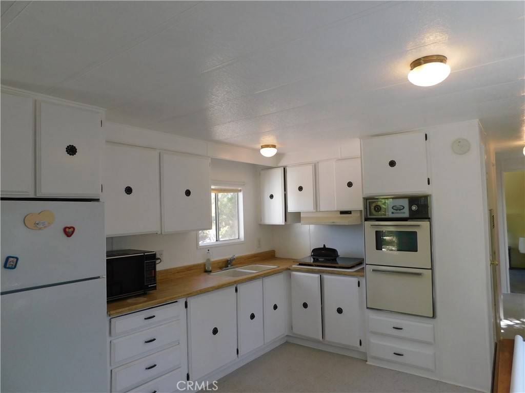45985 Cottonwood Road Newberry Springs, CA 92365 - Photo 51 of 67 a kitchen with granite countertop white cabinets and stainless steel appliances
