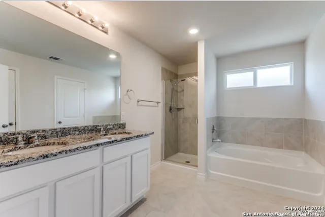 a bathroom with a granite countertop sink a mirror a bathtub and shower