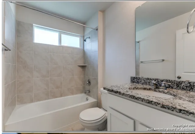 a bathroom with a granite countertop sink a toilet a bathtub and shower