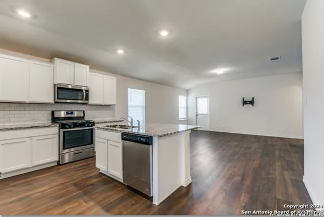 a kitchen with stainless steel appliances granite countertop a stove a sink and a microwave