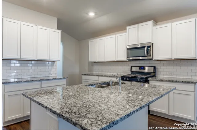 a kitchen with stainless steel appliances granite countertop a sink stove and microwave