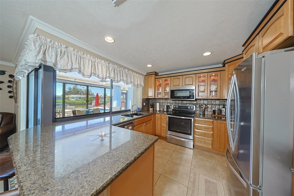 914 Chipaway Drive Apollo Beach, FL 33572 - Photo 9 of 49 a kitchen with stainless steel appliances granite countertop a refrigerator a oven and white cabinets with wooden floors
