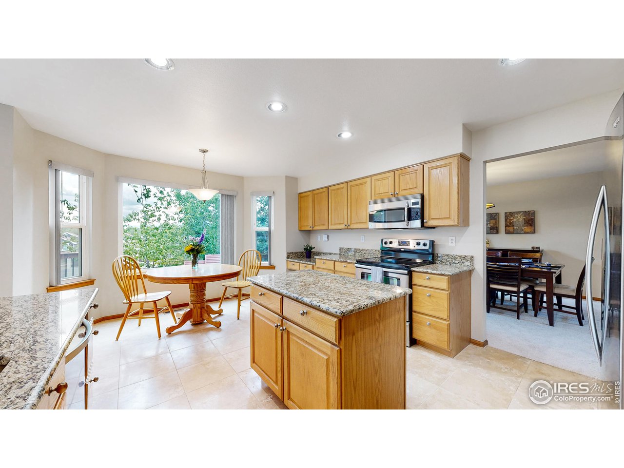 9951 South Spring Hill Place Highlands Ranch, CO 80129 - Photo 3 of 40 a open kitchen with stainless steel appliances granite countertop a stove top oven a sink dishwasher a dining table and chairs with wooden floor