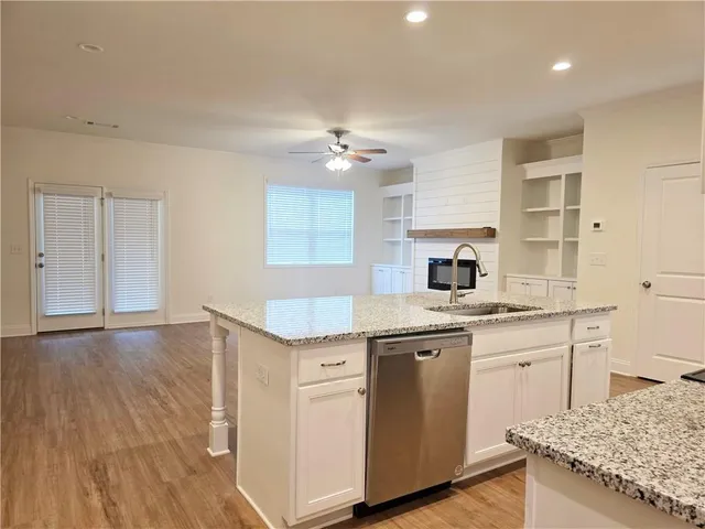 a kitchen with granite countertop a sink cabinets and wooden floor