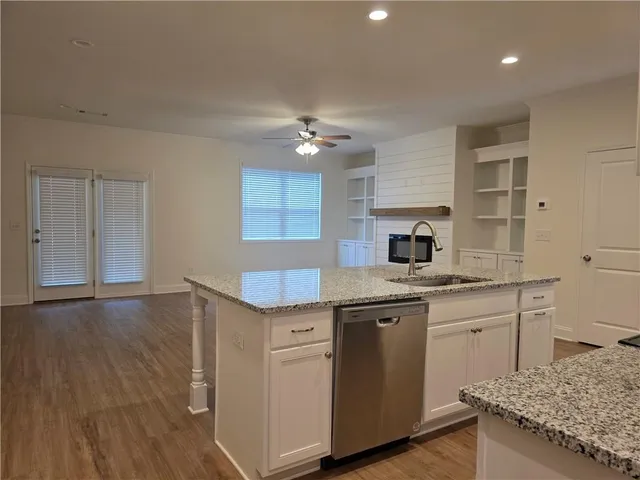 a kitchen with granite countertop a sink cabinets and wooden floor