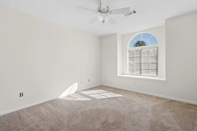 an empty room with a window and ceiling fan