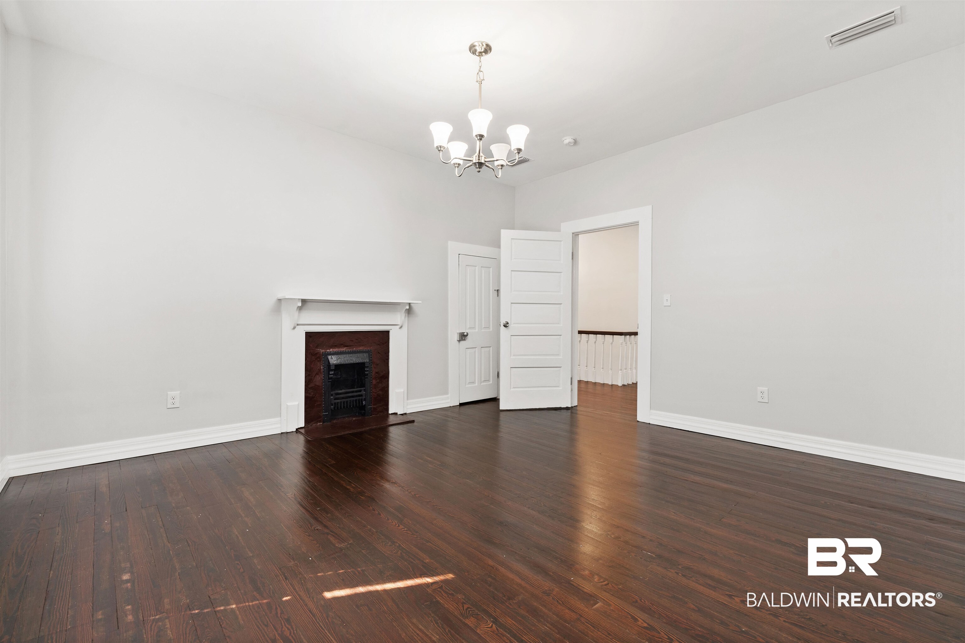 407 East 2nd Street Bay Minette, AL 36507 - Photo 25 of 40 Unfurnished living room with dark wood-style flooring, a fireplace, and a chandelier