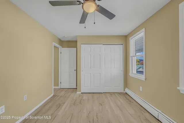 a view of an empty room and window with a chandelier fan